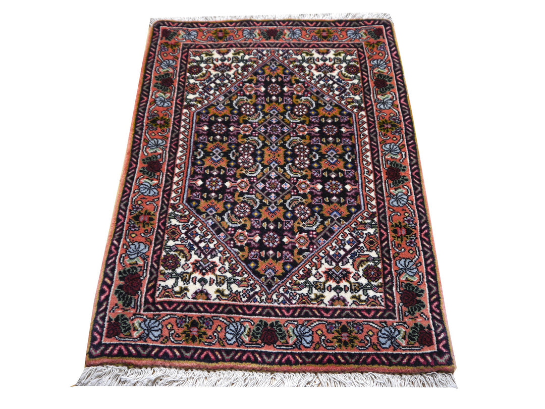 Bidjar Tekab Teppich in Schrägansicht: Terrakottabordüre mit Rosen, Elfenbein-Eckzwickel und dichtes marineblaues Herati-Feld
