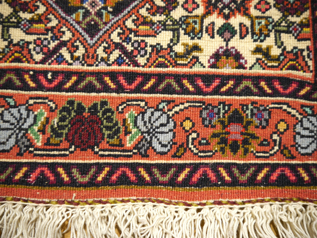 Makroaufnahme der Bidjar-Tekab-Bordüre mit einzeln erkennbaren Knoten bei ca. 400.000–500.000 Knoten/m², Rosenranke auf Terrakotta und Baumwollfransen