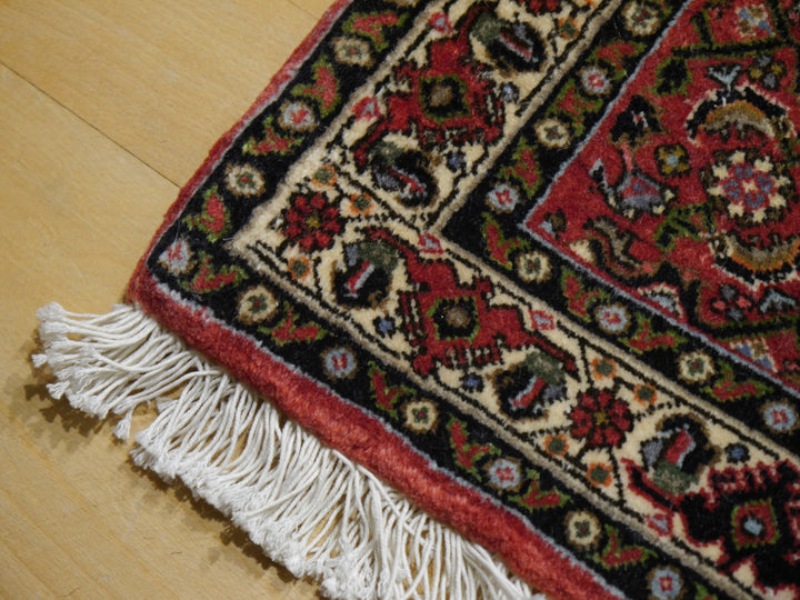 Leicht umgeschlagene Ecke des Bidjar Tekab mit Elfenbein-Palmettenbordüre, roter Außenkante und flach gearbeiteten Baumwollfransen
