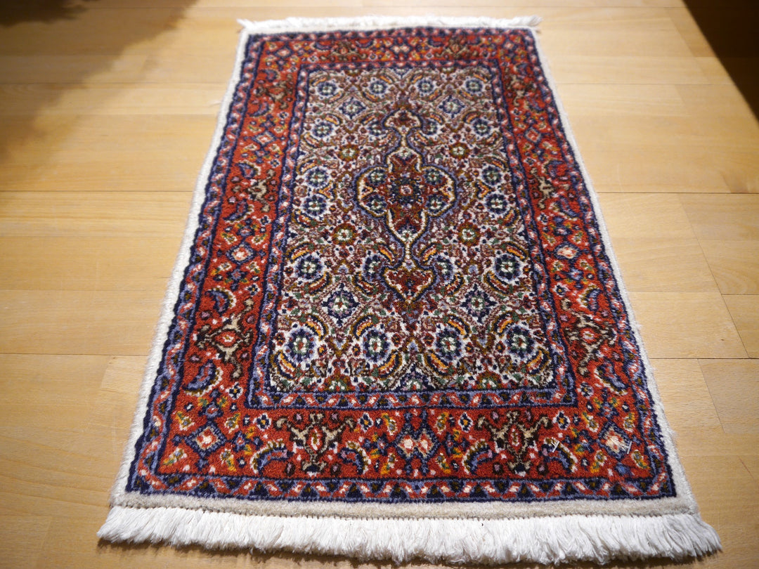 Moud Birjand rug on a light oak floor, ivory field and rust red border, angled full view | 13377
