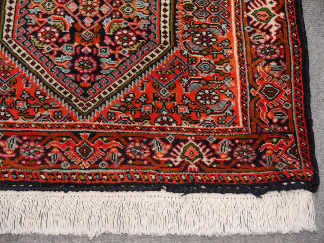 Corner detail of the Tekab Bidjar runner: navy palmette border, ivory guard stripes and the flat-finished cotton fringe